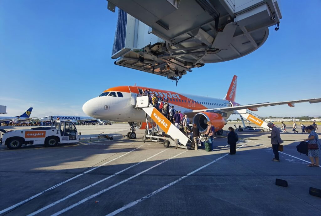 Passengers boarding an easyJet Airbus by the front and rear stairs, with Ryanair aircraft parked in the background